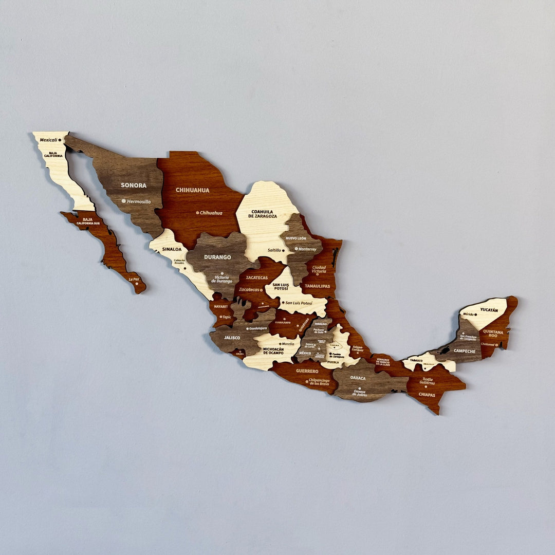 Layered wooden map of Mexico on a pale gray-blue wall, states in cream, gray-brown and mahogany wood, each labeled with its name and capital
