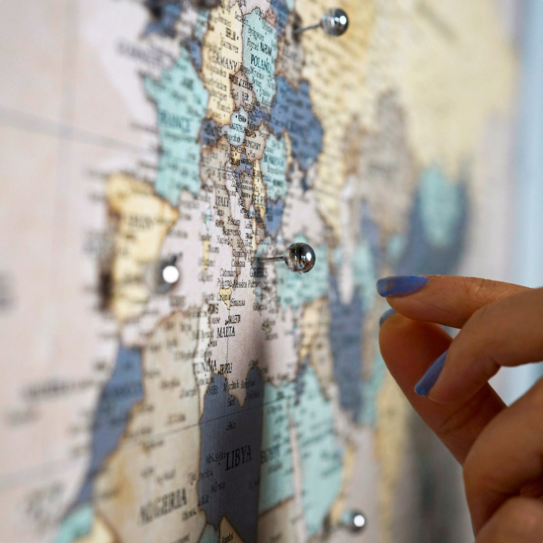a large colorfull canvas world map hanged on a grey wall 