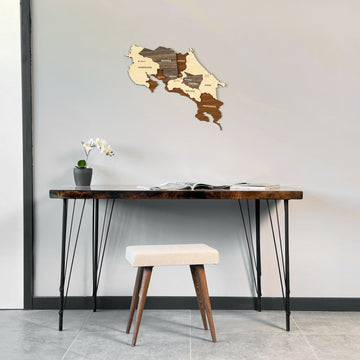 Costa Rica wooden wall map above a hairpin-leg desk with a cream stool, wide room view
