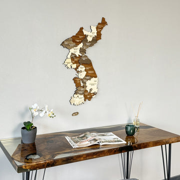 Korea wooden wall map above the end of a resin desk with an orchid