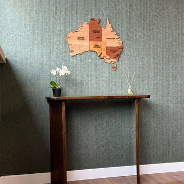 Wooden Australia map on a green wall above a console table, wide room view