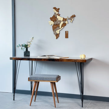 Layered wooden India map at the top of a wide shot with a desk and gray stool