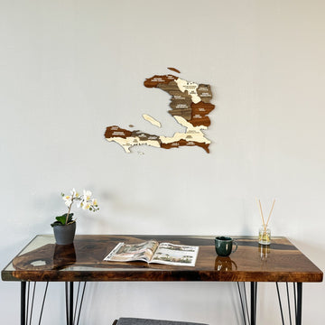 Haiti wooden wall map on a gray wall above a resin desk with an orchid
