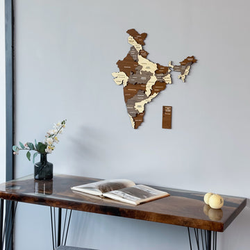 Wooden India map centered on the wall above a walnut desk with an open book