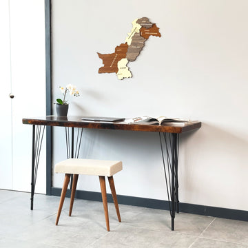 Small Pakistan wooden wall map above a desk with a cream stool, seen from the right