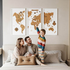 White framed cork push pin world map in three panels above a bed, with a family and a child pointing