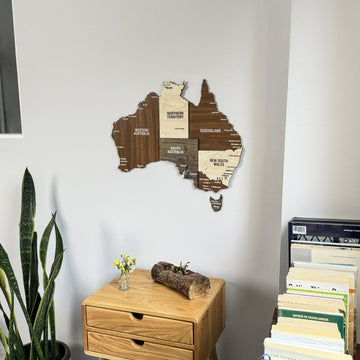Australia wooden wall map beside a window frame, above a drawer table