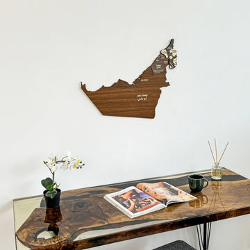 United Arab Emirates wooden wall map above a live-edge desk corner with an open book