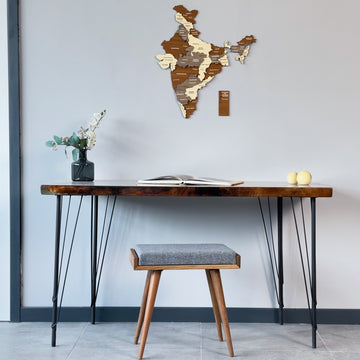 Multicolor wooden India map hung high above a hairpin-leg desk and gray stool, wide room view