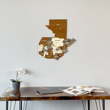 Wooden Guatemala map above the edge of a walnut desk, with an orchid at left