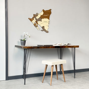 Nicaragua wooden map above a desk and white stool, view with a dark door frame at left
