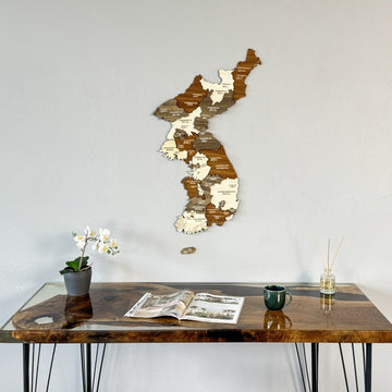 North and South Korea wooden wall map on a gray wall above a resin desk with an orchid