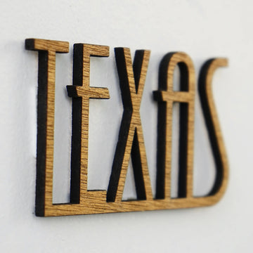 Close-up of the wooden TEXAS cut-out lettering with dark edges, shown beside the Texas wall map