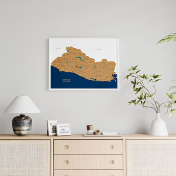 White framed El Salvador cork map with a navy Pacific Ocean, front view above a sideboard
