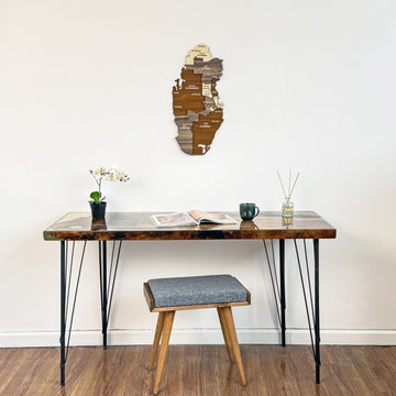 Small Qatar wooden wall map high on a white wall above a desk and stool, full-room view