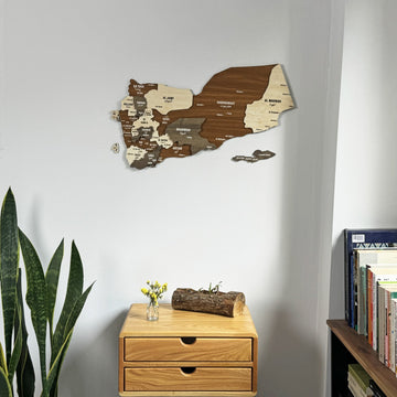 Yemen wooden wall map above a wooden chest of drawers with a log decor piece and a snake plant