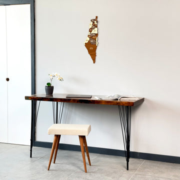 Palestine wooden wall map beside a white door, above a desk with a cushioned stool
