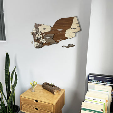 Yemen wooden wall map above a chest of drawers with a stack of books at right