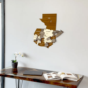 Wooden Guatemala wall map above a walnut desk with an open magazine, medium view