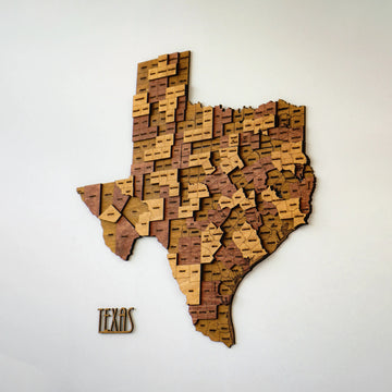 Large Texas 3D wood map with layered county pieces in light and dark brown, side angle on a white wall
