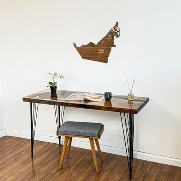 Small United Arab Emirates wooden wall map above a desk with a gray stool on a wood floor