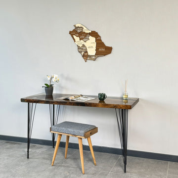 Saudi Arabia wooden wall map above the left side of a desk with a stool below, tight crop