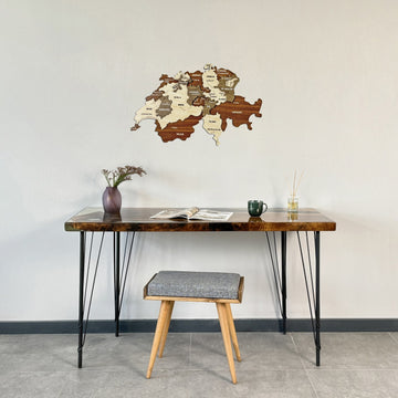 Switzerland wooden wall map above a resin-edged desk with a gray stool, full-room view