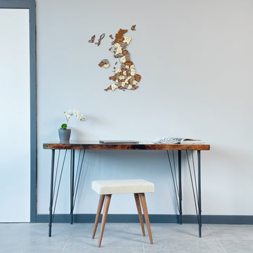 United Kingdom wooden wall map above a hairpin-leg desk with a cream stool, wide room view