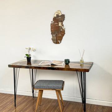 Qatar wooden wall map above a desk with a gray cushioned stool