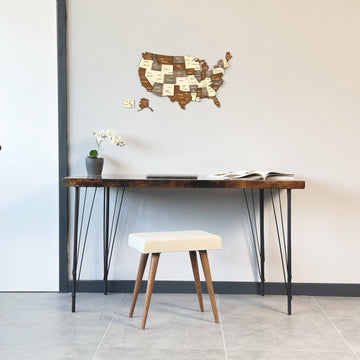 Wooden USA map high on a gray wall above a hairpin-leg desk and cream stool