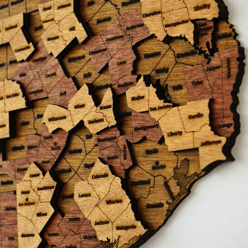 Close-up of layered Texas county pieces with engraved names like Harris, Montgomery and Liberty in wood tones