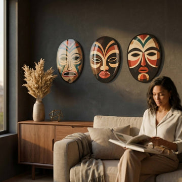 African masks metal wall art set of three on a dark wall behind a woman reading
