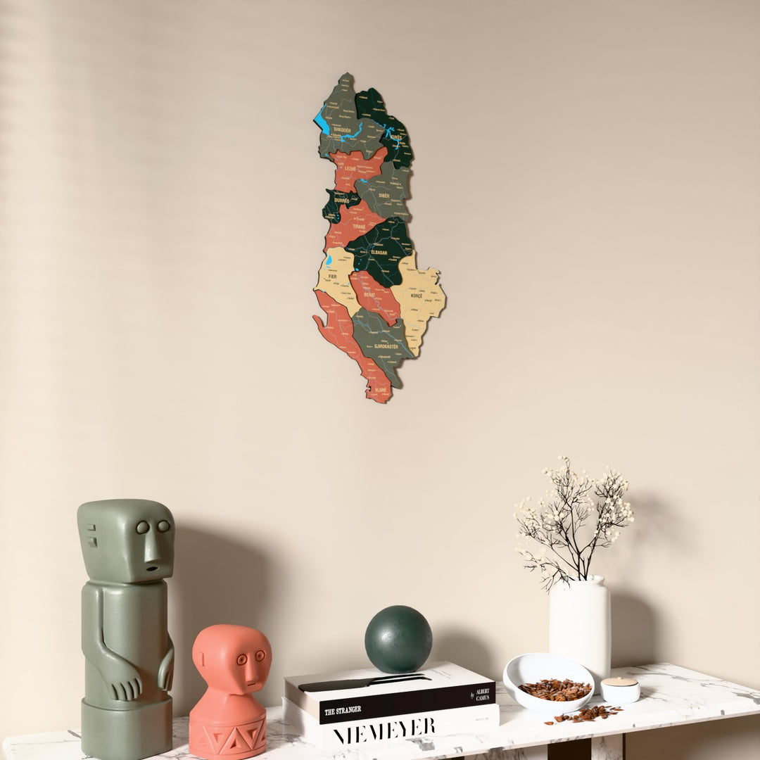 Sage Albania wooden wall map on a beige wall above a console with figurines