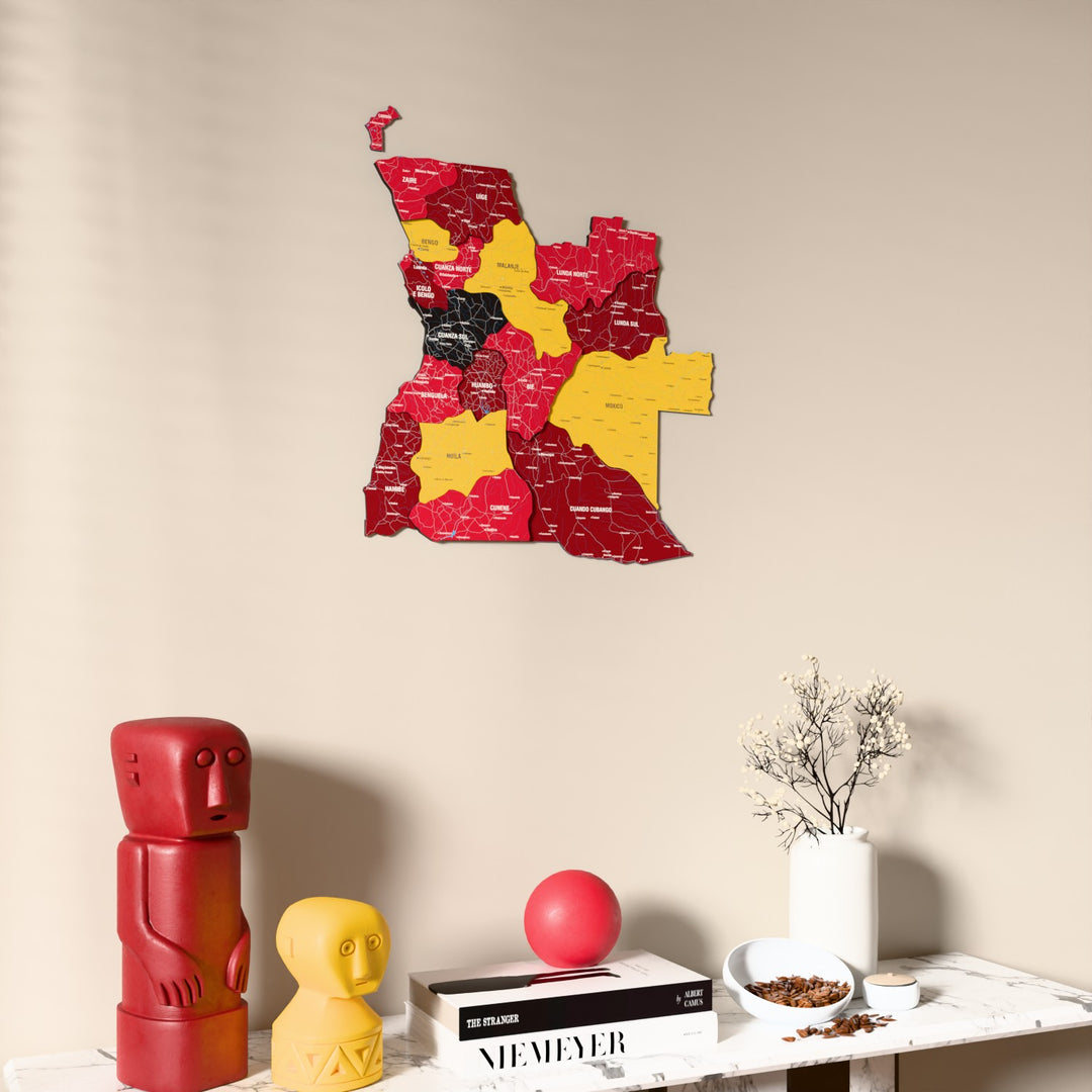 Flag colored Angola wooden wall map on a beige wall above a console with figurines