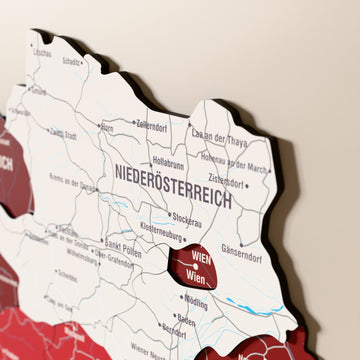 Close-up of the Flag colored Austria wooden wall map with layered regions and printed names