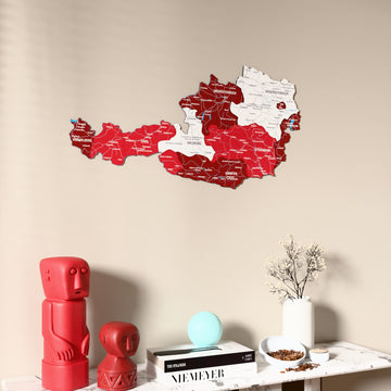 Flag colored Austria wooden wall map on a beige wall above a console with figurines