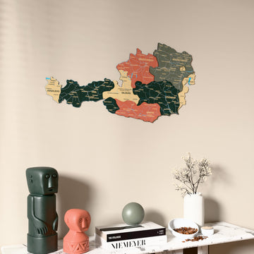 Sage Austria wooden wall map on a beige wall above a console with figurines