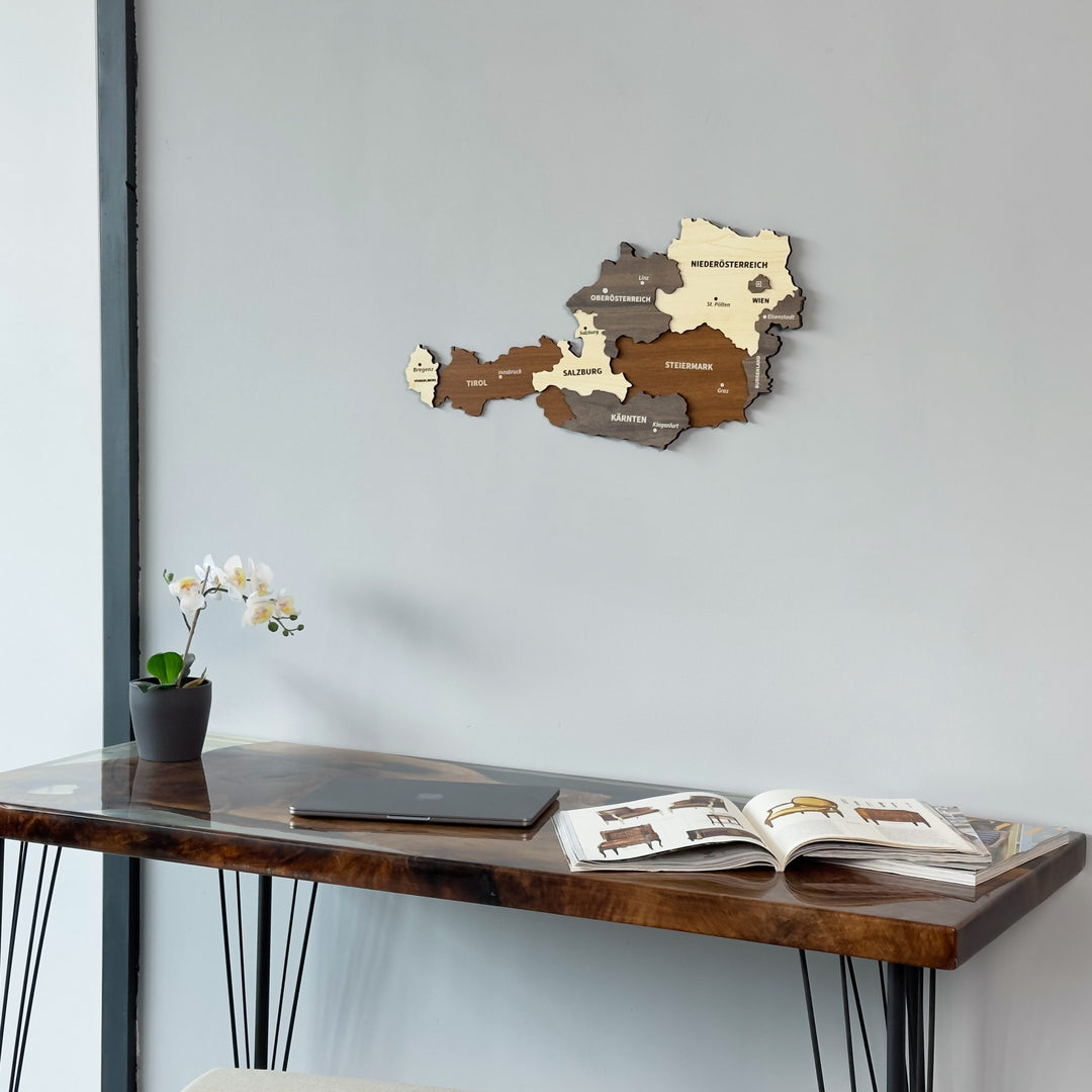 Austria wooden wall map above the corner of a resin desk with a laptop, close view