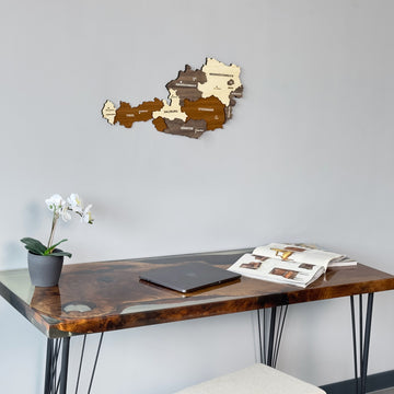 Austria wooden wall map seen from a lower angle above a resin desk with an orchid