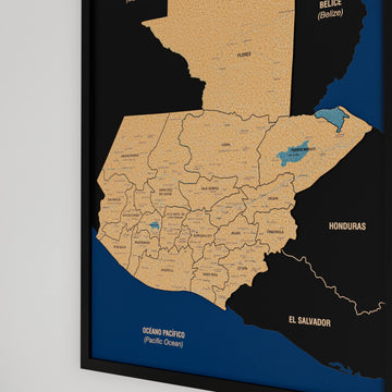 Close-up of department names and the Izabal lake on a black-framed Guatemala cork map, Pacific coast below