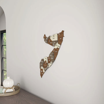 Somalia wooden wall map beside a window arch, with a tray on the desk below
