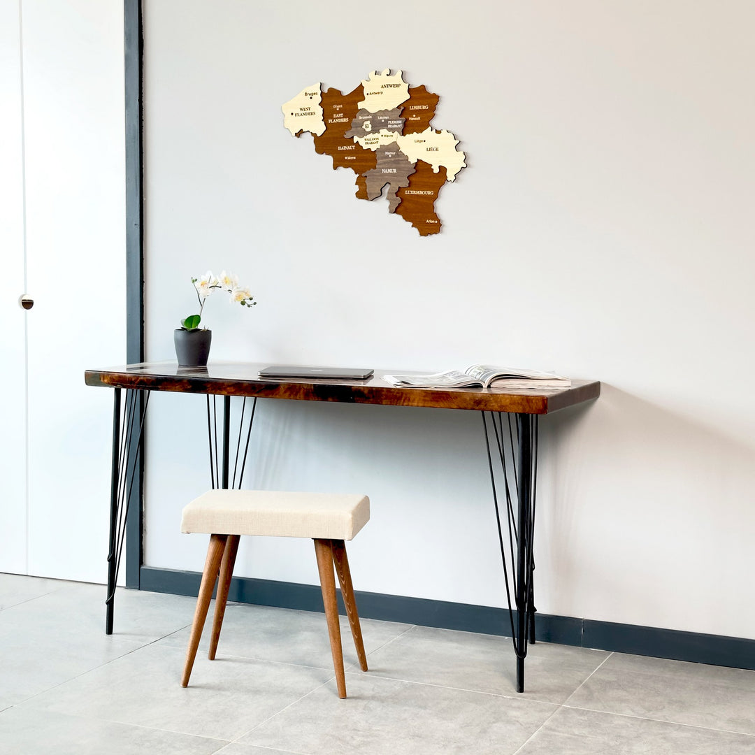 Belgium wooden wall map above a dark desk with a white door frame at left