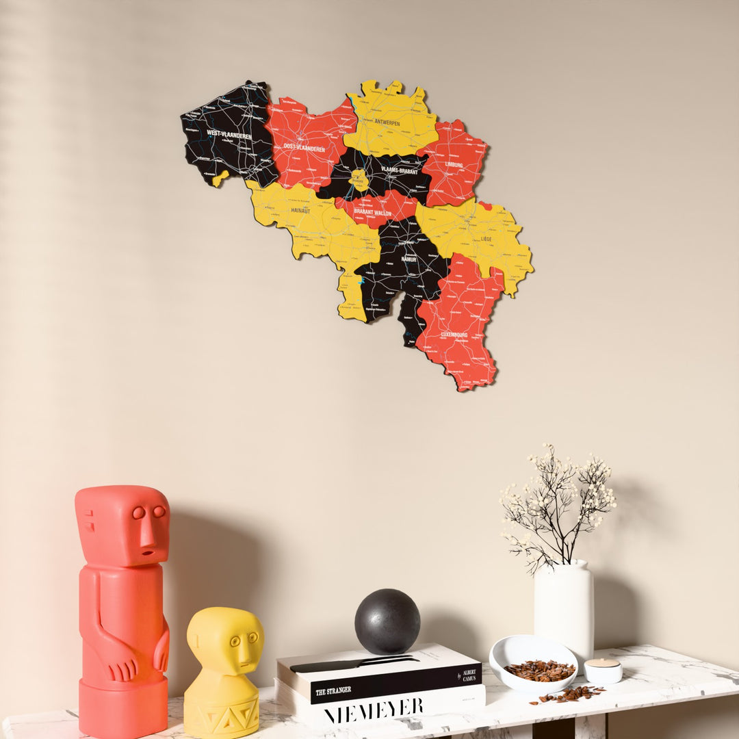 Flag colored Belgium wooden wall map on a beige wall above a console with figurines