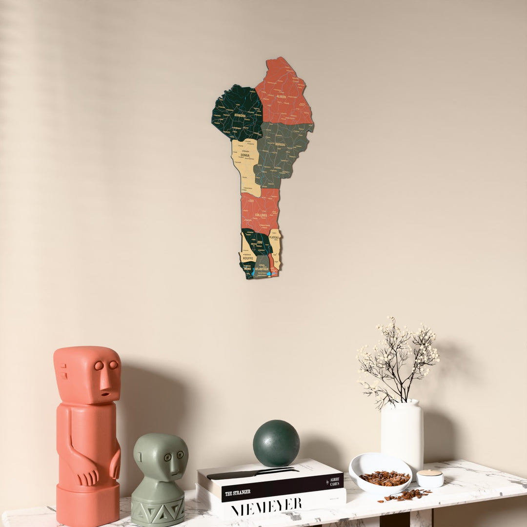 Sage Benin wooden wall map on a beige wall above a console with figurines