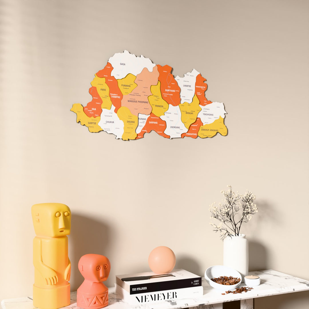 Flag colored Bhutan wooden wall map on a beige wall above a console with figurines