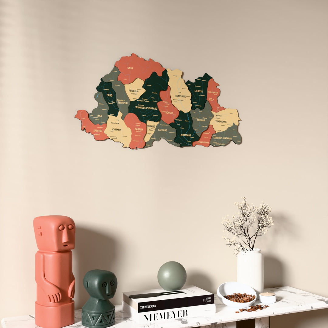 Sage Bhutan wooden wall map on a beige wall above a console with figurines