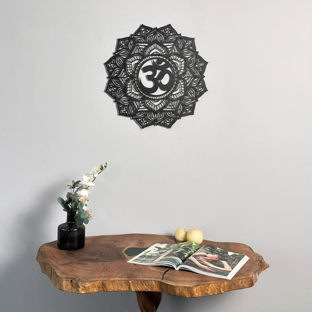 Black OM mandala metal wall art above a live-edge wood table with a vase of flowers