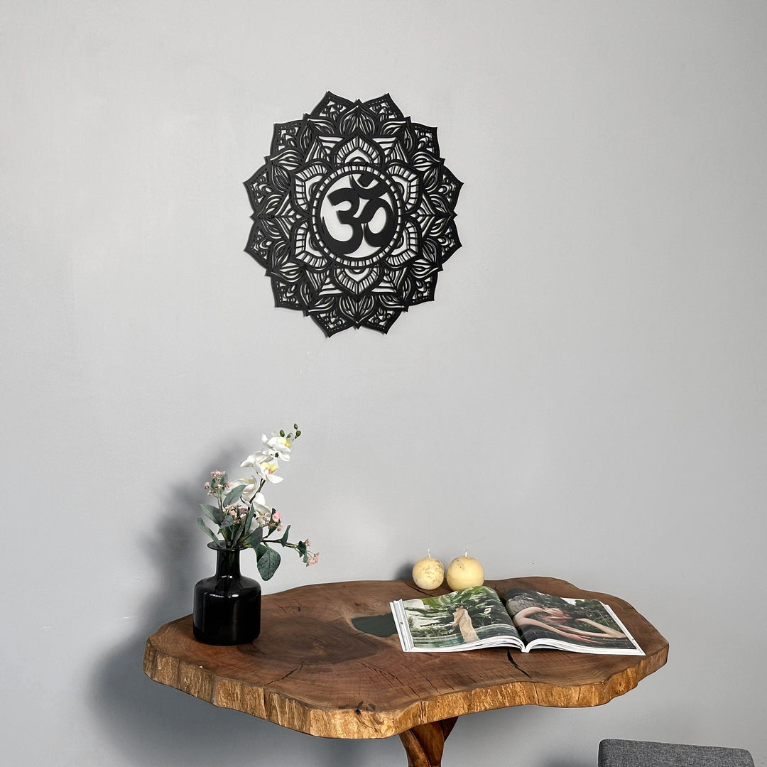 Black OM mandala metal wall art centered over a live-edge table with two pears