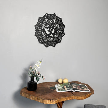 Black OM mandala metal wall art centered over a live-edge table with two pears