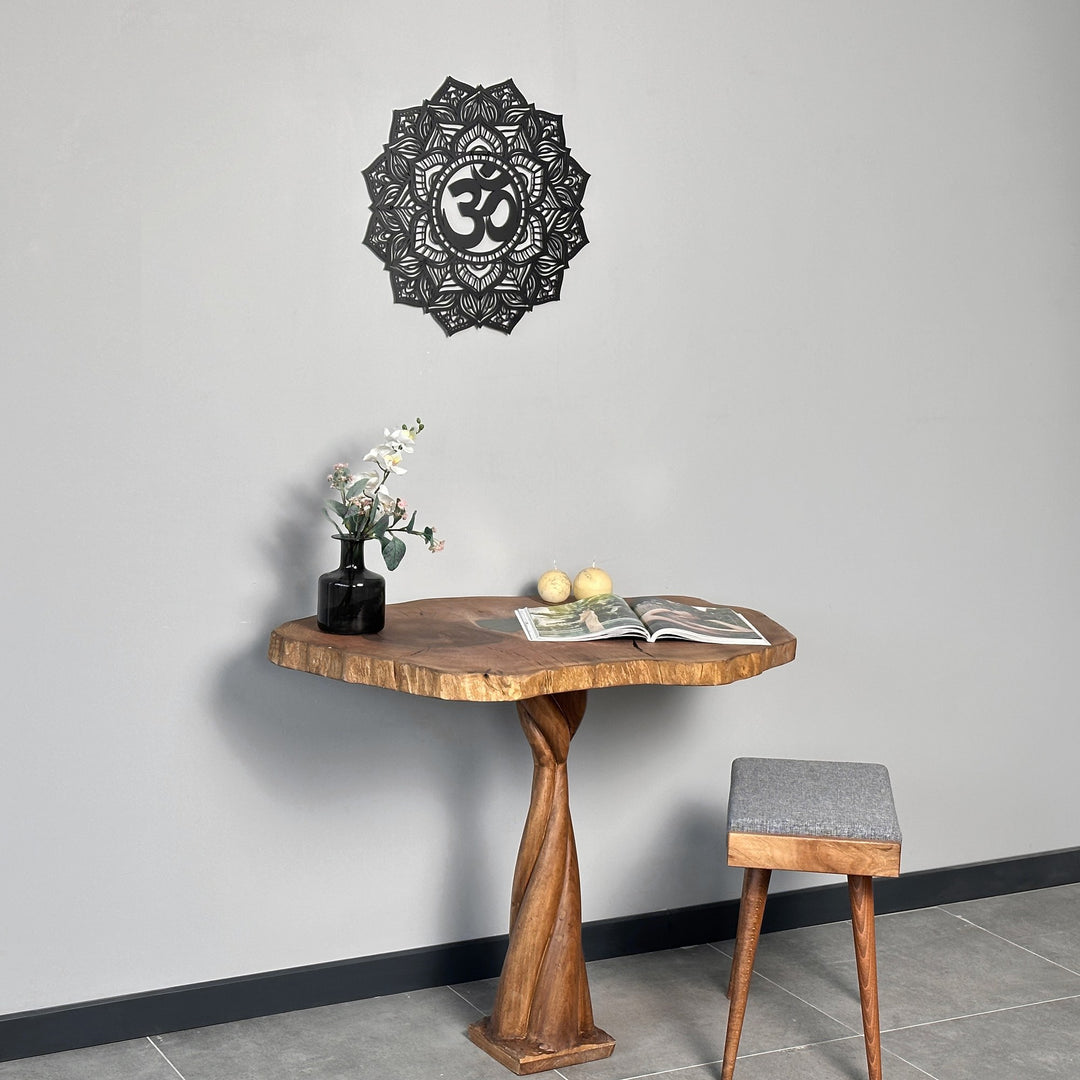 Small black OM mandala metal wall art above a live-edge pedestal table with a gray stool